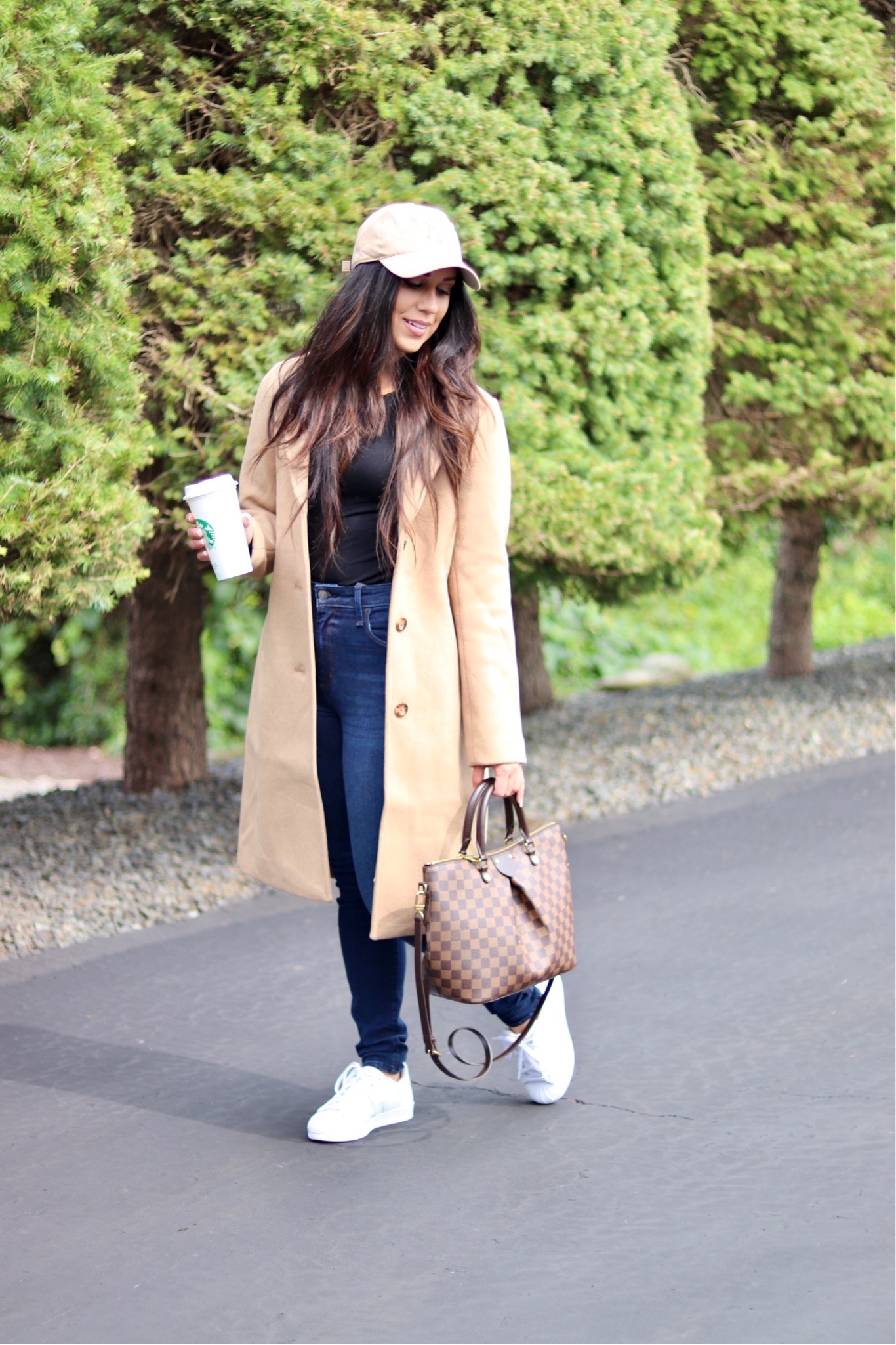 woman wearing dad coat, jeans, shirt, and cap